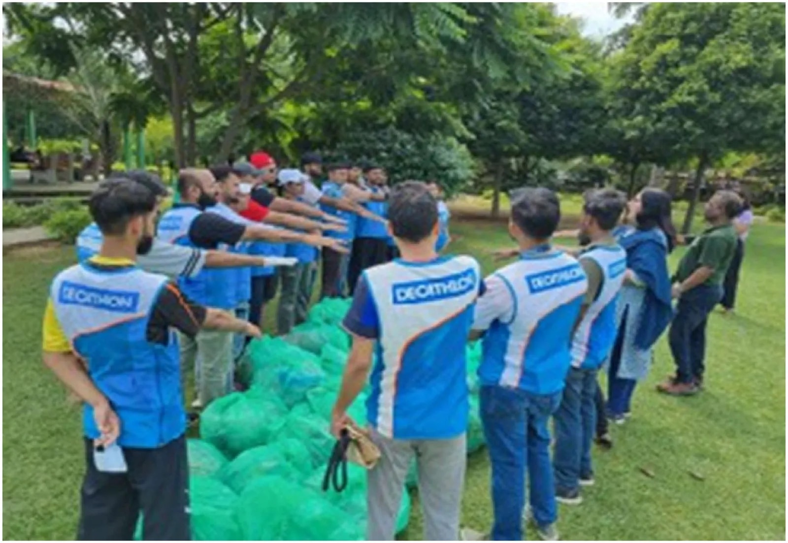 Volunteers in team jerseys standing beside filled collection bags in a park